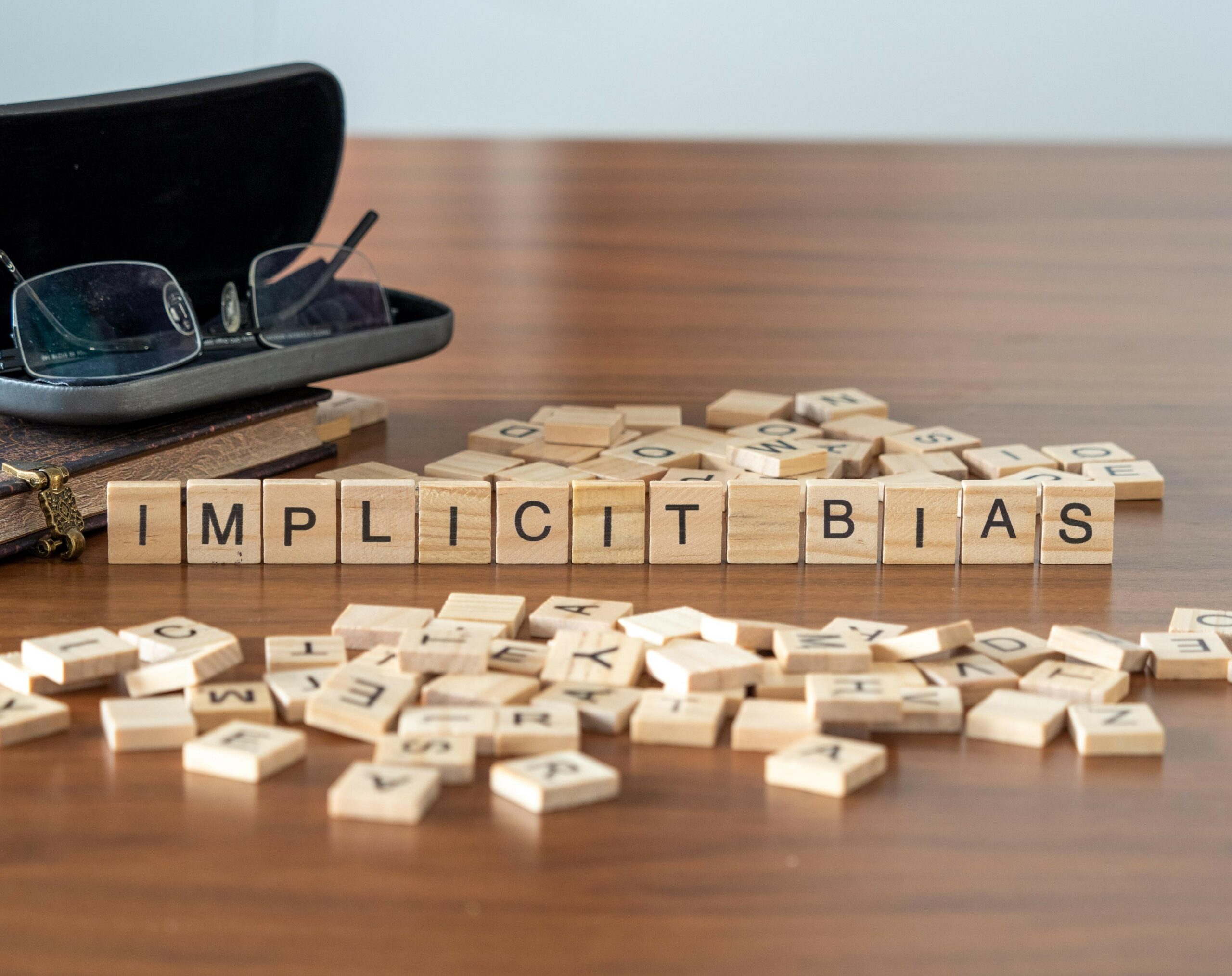 Scrabble tiles on a wood table spelling Implicit Bias