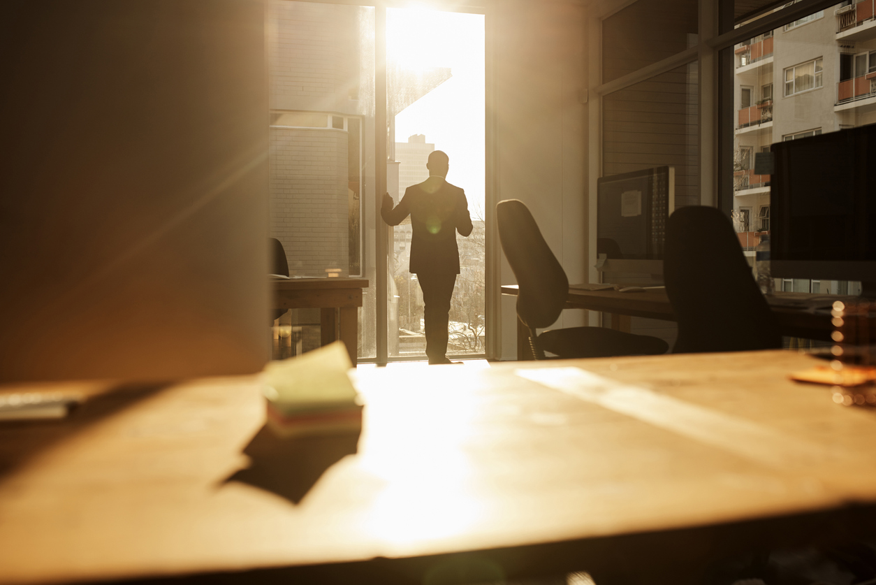 Rearview shot of a mature businessman looking through a window in an office