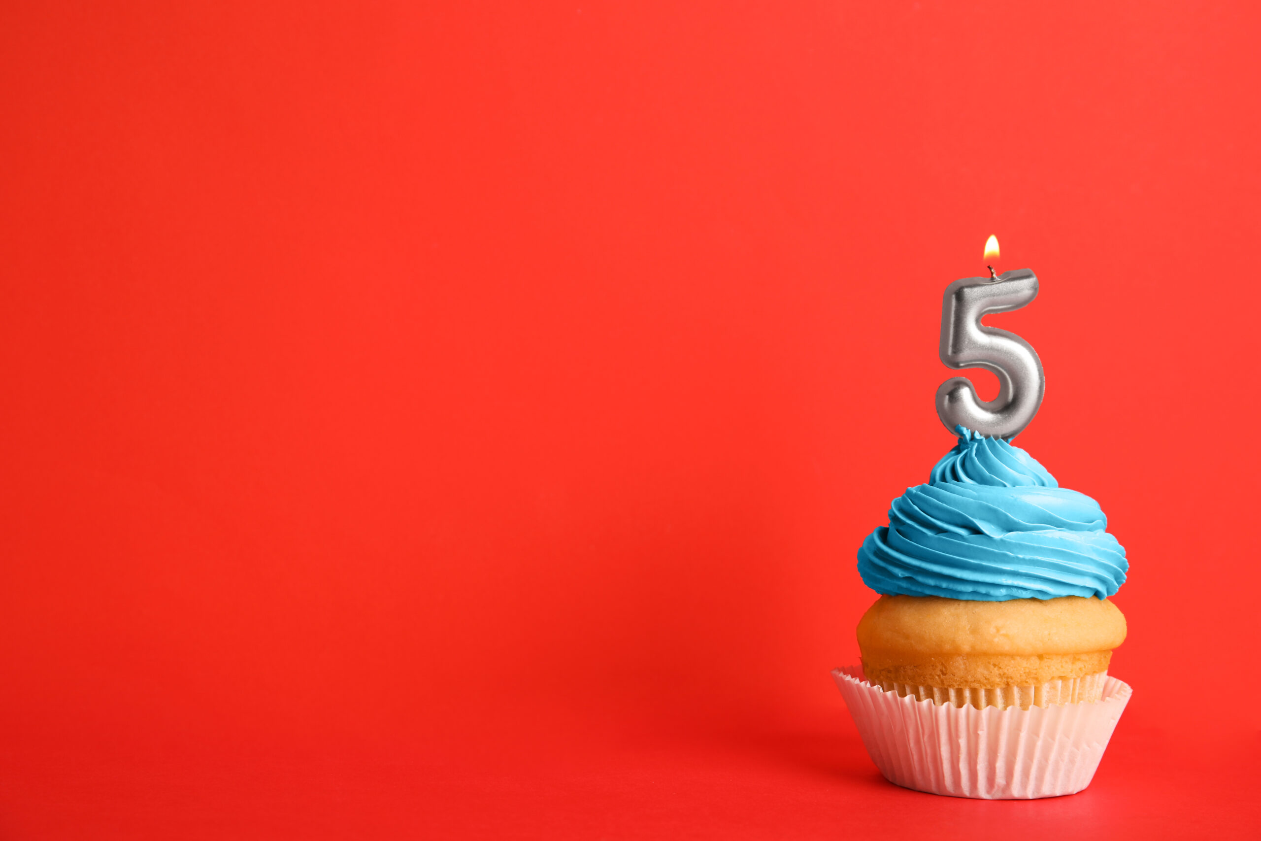 Birthday cupcake with number five candle on red background